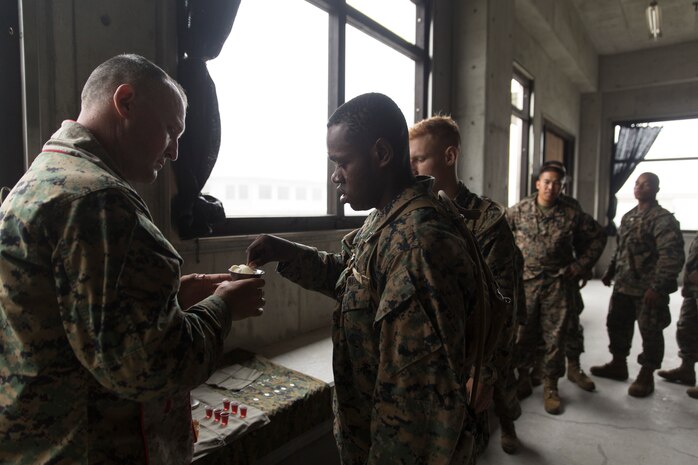 Lance Cpl. Kishun Parrott, an initial provision chief with Combat Logistics Company 36, takes a chip from Lt. Cmdr. Harvey Macklin, regimental chaplain with Combat Logistics Regiment 35, during a the communion part of sermon as part of Exercise Dragon Fire 2014 at Combined Arms Training Center Camp Fuji, Japan, July 13. Parrott said the sermon made him want to be a leader both spiritually and in the Marine Corps. Macklin conducted the sermon for Combat Logistics Company 36 Marines and augments as a pause from military operations on urban terrain to boost morale and foster unit cohesion. 
