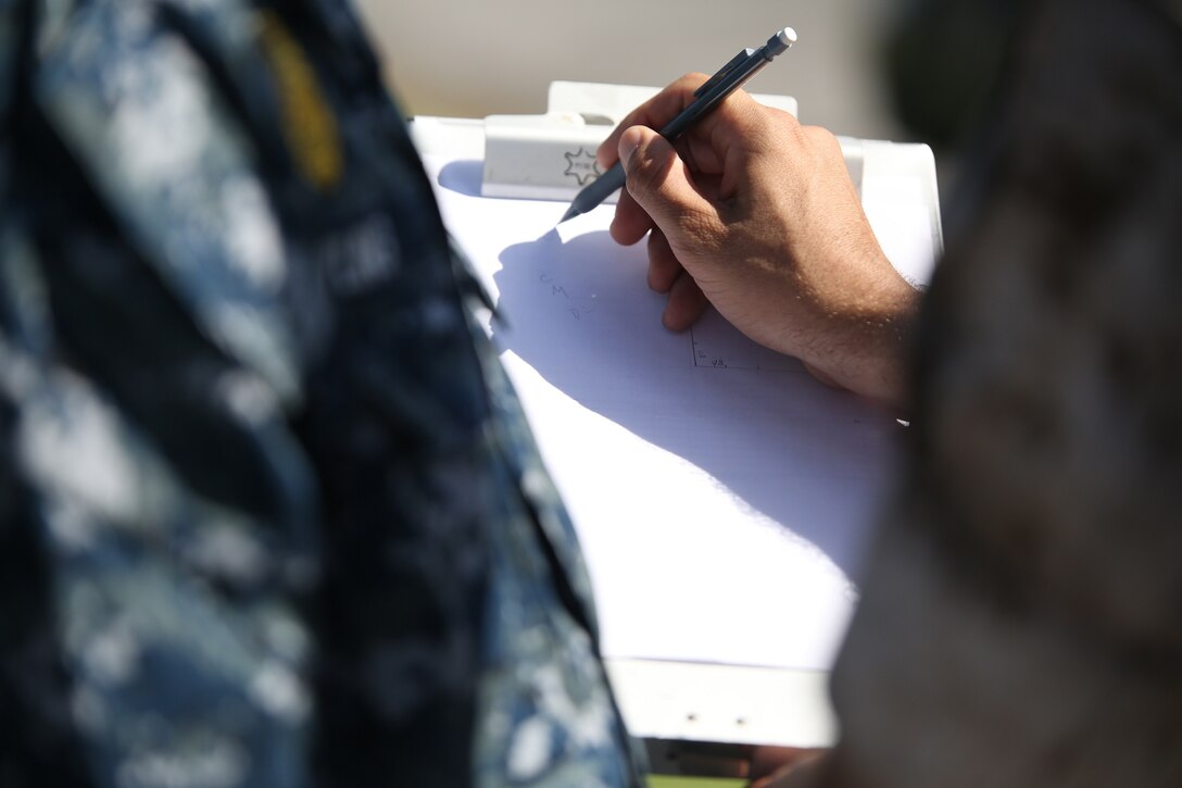 Gunnery Sgt. Antonio Lopez, right, instructs Petty Officer 3rd Class Andrew Dowling on roadway measurement calculations July 14 at Camp Foster as part of the Traffic Collision Investigation Course. The day of practical application training took the service members out of the classroom and onto the streets. The hands-on training familiarized the service members with what to look for when at the scene of an accident. Lopez is a Calipatria, California, native and an accident investigator with the Marine Detachment at Lackland Air Base, Training Command, Training and Education Command. Dowling is a Norton, Ohio, native and master-at-arms 3 with Commander Fleet Activities Okinawa Security. (U.S. Marine Corps photo by Lance Cpl. Wes J. Lucko/Released)