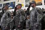 Army Command Sgt. Maj. Stanley Massengale, Army Col. David Jones and Army Command Sgt. Maj. William Gill salute during the singing of the national anthem at Camp Arifjan, Kuwait, Dec. 27, 2011, before the transfer of authority ceremony between the Tennessee Army National Guard's 230th Sustainment Brigade and the North Carolina Army National Guard's 113th Sustainment Brigade. Massengale, the command sergeant major for the 230th SB, cased his unit's colors while the 113th SB's commander and command sergeant
major, Jones and Gill, unfurled their flag to symbolize the transfer of
command for the unit.