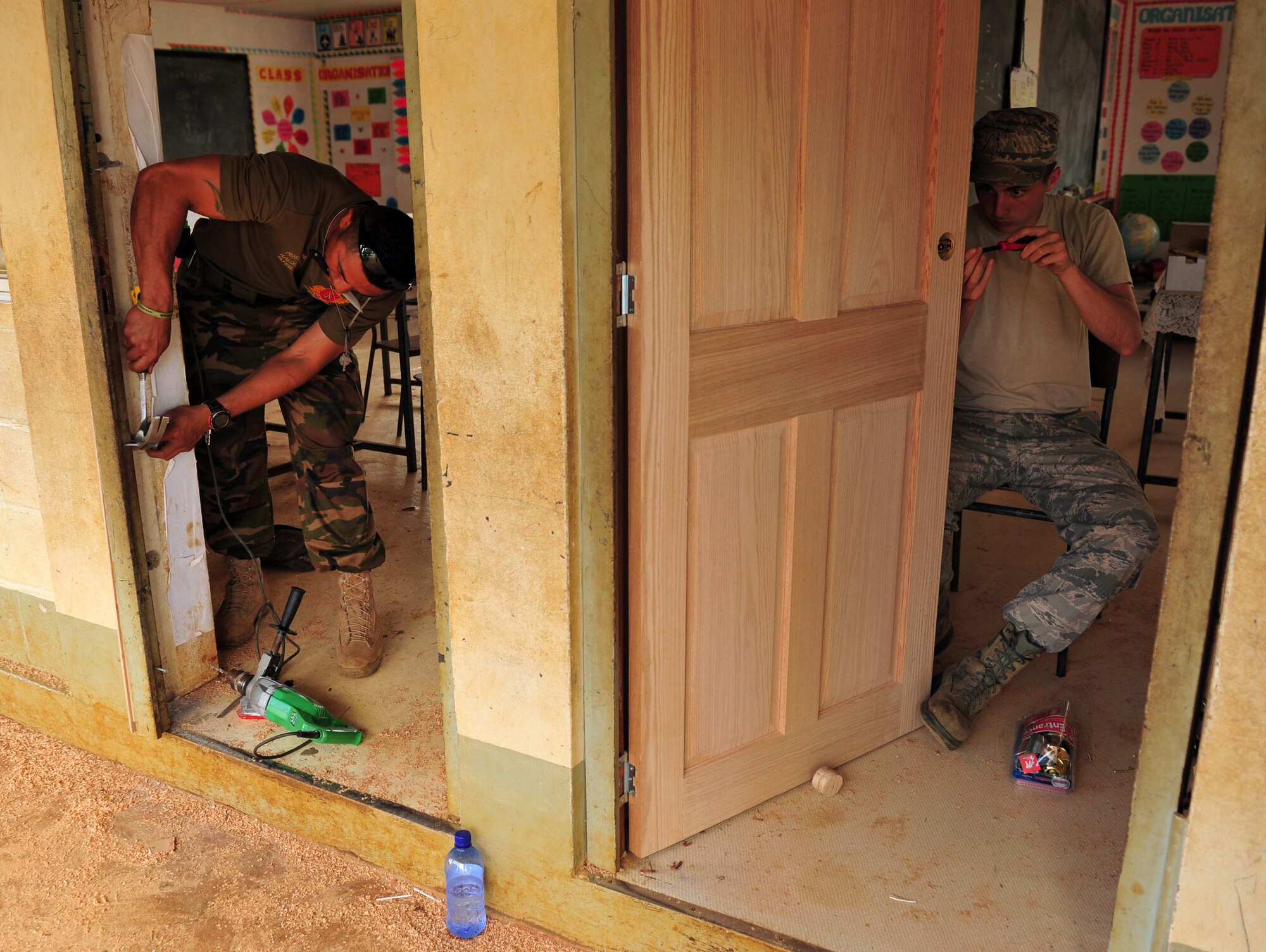 Tongan armed forces Pvt. Benny Kalonihea, left, and Airman 1st Class Devin Laird replace doors July 17, 2014, at the Neiafu Government Primary School, Neiafu, Tonga. Military electricians, structural craftsmen, carpenters and plumbers worked together to repair and replace doors, locks, windows, wiring, partitions, sinks, faucets, toilets and various additional requirements during Operation Pacific Angel-Tonga. Pacific Angel is a total force, joint and combined humanitarian assistance operation, led by Pacific Air Forces. Kalonihea is a carpenter and Laird is an electrician. (U.S. Air Force photo/Staff Sgt. Rachelle Coleman)