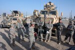 Citizen-Soldiers with the Kentucky National Guard's 223rd Military Police Company conduct a briefing at Camp Liberty, Iraq, before an escort mission in 2008 in front of their vehicles. (Army National Guard photo by Staff Sgt. Jim Greenhill)