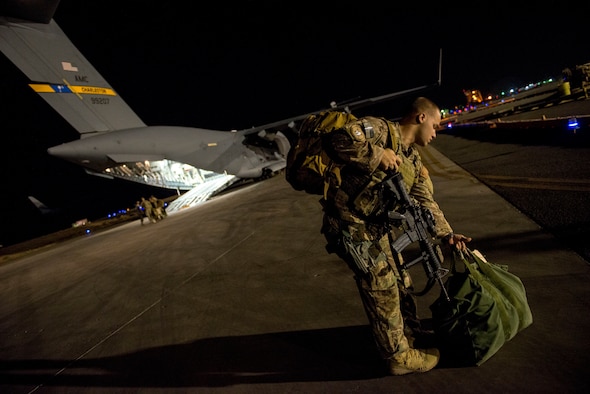 Airman 1st Class Marc Francesconi loads his gear in preparation for takeoff in a C-17 Globemaster III June 29, 2014, in Southwest Asia. Francesconi is a member of the 386th Expeditionary Security Forces Squadron fly away security team. Security forces members provide security of personnel and aircraft around the world. (U.S. Air Force photo/Staff Sgt. Jeremy Bowcock)