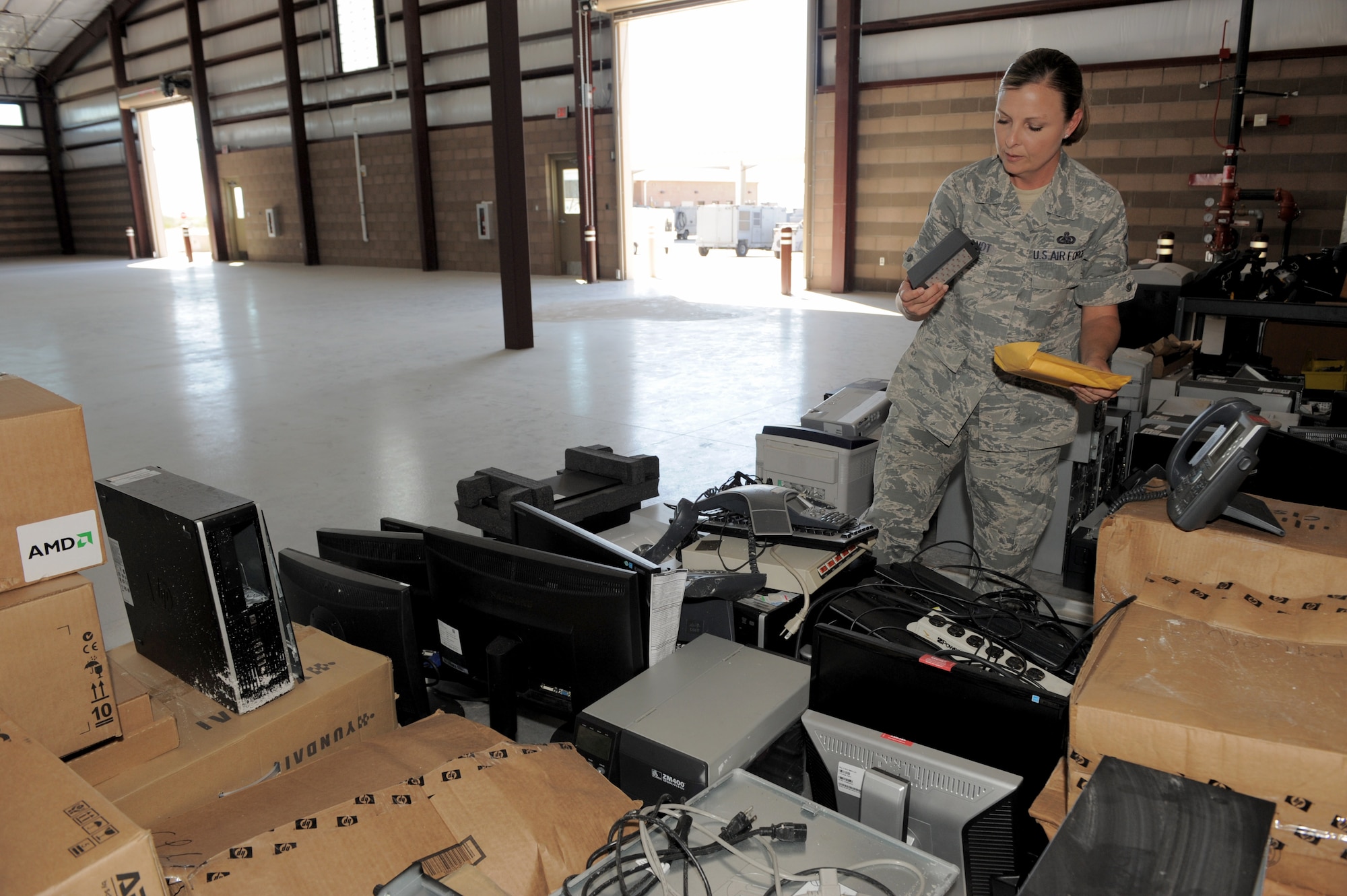 U.S. Air Force Master Sgt. Shawna Brabandt, 355th Logistics Readiness Squadron customer support section chief, sifts through an array of electronic equipment at Davis-Monthan Air Force Base, Ariz., July 21, 2014. The equipment was salvaged from the 355th LRS customer service building after a monsoon storm left it heavily damaged July 13. (U.S. Air Force photo by Airman 1st Class Chris Drzazgowski/Released) 