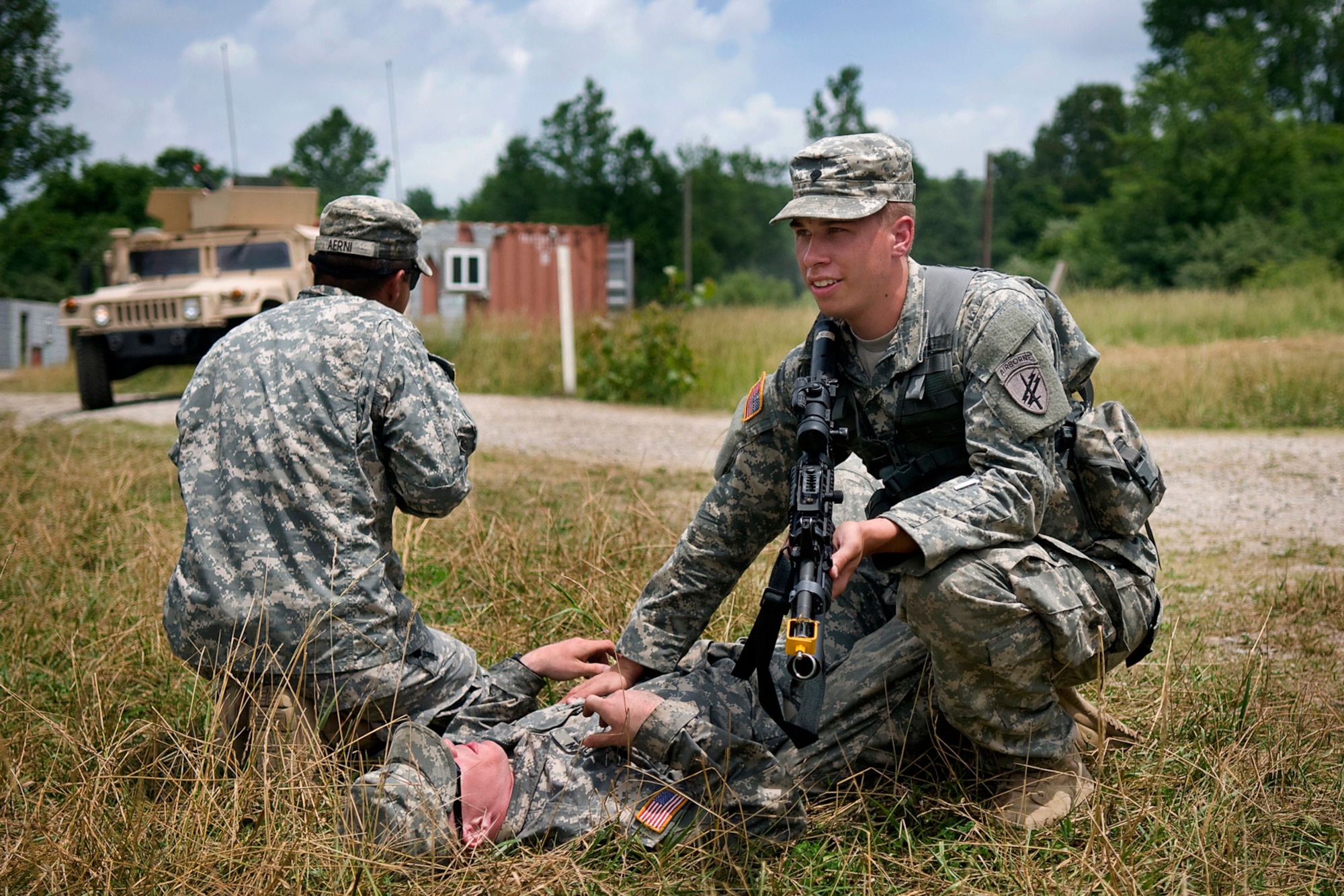 U.S. Army Spc. Alexander Woodall tends to a simulated wounded U.S. Army Spc. Jeremy Olson as U.S. Army Spc. Joshua Aerni looks for enemy forces during a training scenario at Camp Atterbury Joint Maneuver Training Center, Ind., June 19, 2014. All three are 316th Psychological Operations Company PSYOP specialists, and along with more than 30 of their fellow Soldiers from Grissom Air Reserve Base, Ind., took part in an intensive military support operations training at Camp Atterbury. (U.S. Air Force photo/Tech. Sgt. Mark R. W. Orders-Woempner)
