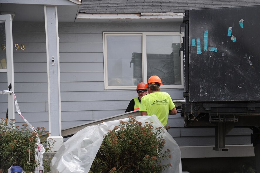 Contractors move parts out of a house during a demolition in housing areas at Fairchild Air Force Base, Washington, July 22, 2014. Balfour Beatty Communities is getting rid of a number of houses to meet the Department of Defense's requirement of 641 homes that is needed for the base. (U.S. Air Force photo by Airman 1st Class Janelle Patiño/Released)