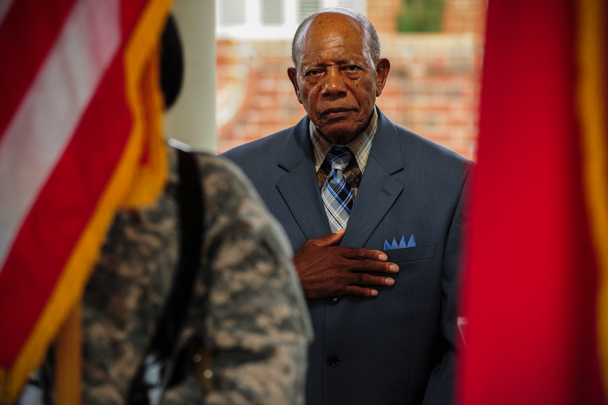 Retired Staff Sgt. Elbert Scott places his hand over his heart during the playing of the national anthem at a medal presentation ceremony in his honor, July 21, 2014, in downtown Goldsboro, North Carolina. Scott was presented six medals for his service during World War II and the Korean War. (U.S. Air Force photo/Airman 1st Class Brittain Crolley)