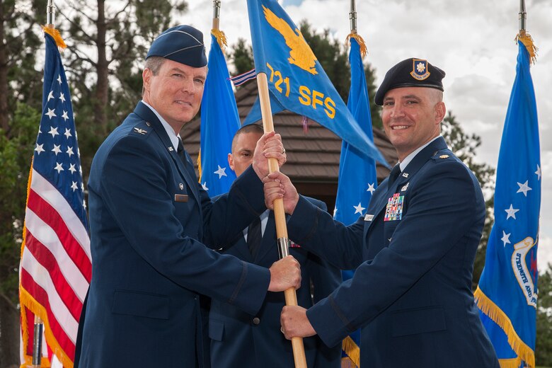 CHEYENNE MOUNTAIN AIR FORCE STATION, Colo. – Col. Travis Harsha (left), 721st Mission Support Group commander, passes the 721st Security Forces Squadron guidon to Maj. Kevin Lombardo, 721st SFS incoming commander, during the 721st SFS change of command ceremony July 11 here. Lombardo assumes command of the 721st SFS which is responsible for protecting the overall security of the people and priority resources at Cheyenne Mountain AFS. (U.S. Air Force photo/Craig Denton)