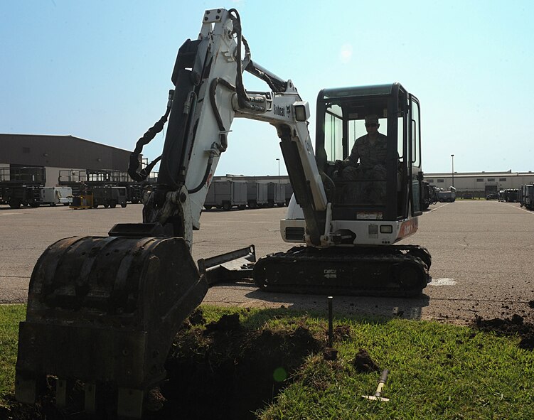 Tech. Sgt. Eric Birr, 22nd Civil Engineer Squadron pavements and equipment supervisor, uses a mini excavator, July 22, 2014, at McConnell Air Force Base, Kan. Burr is digging a hole to install a 40-foot flagpole in front of a hangar for the 22nd Aircraft Maintenance Squadron. (U.S. Air Force photo/Airman 1st Class David Bernal Del Agua)