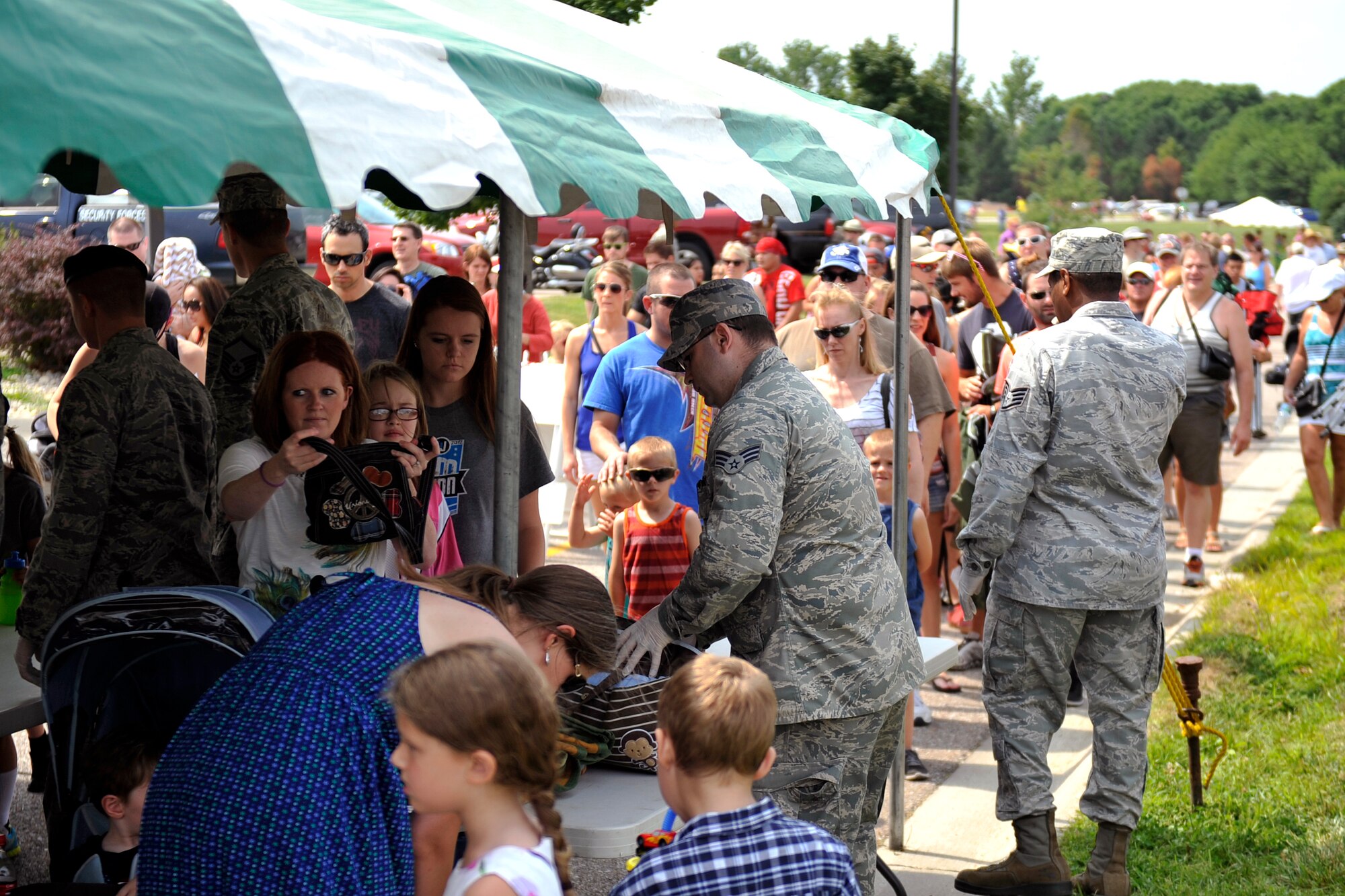 Patrons wait in line as security personnel inspect bags at the entrance to the 2014 Defenders of Freedom Open House and Air Show July 19 at Offutt Air Force Base, Nebraska.  Airmen worked as quickly as they could to ensure everyone had a safe enjoyable experience  (U.S. Air Force photo by Jeff W. Gates/Released)