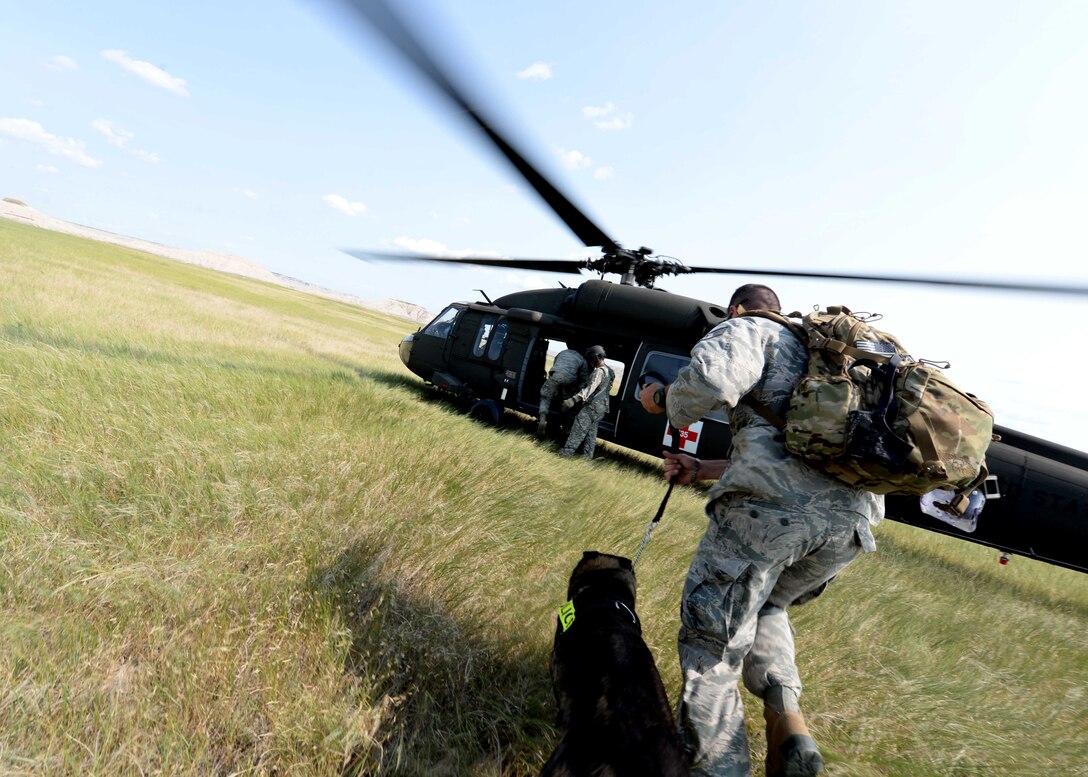 Staff Sgt. John Whisman, 28th Security Forces Squadron Military Working Dog trainer and handler, and his dog, Batu, run to a helicopter during a day of training in the outskirts of Rapid City, S.D., July 17, 2014. Batu went through helicopter familiarization training to ensure readiness for future missions. (U.S. Air Force photo by Airman 1st Class Rebecca Imwalle/ Released) 