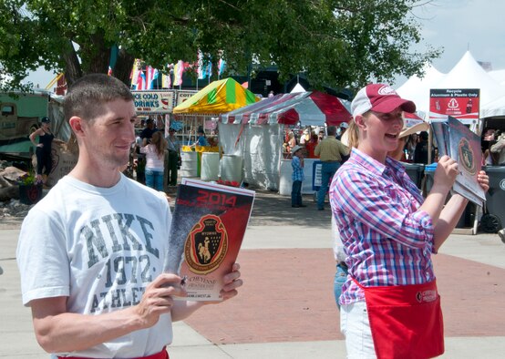 Airmen 1st Class Rusty Menard and Heather Seifert Olson, 90th Security Forces Squadron, sell souvenir programs near the entrance of Frontier Park during Cheyenne Frontier Days July 19, 2014. Approximately 70 defenders signed up to work each day of CFD. (U.S. Air Force photo by Airman 1st Class Jason Wiese)