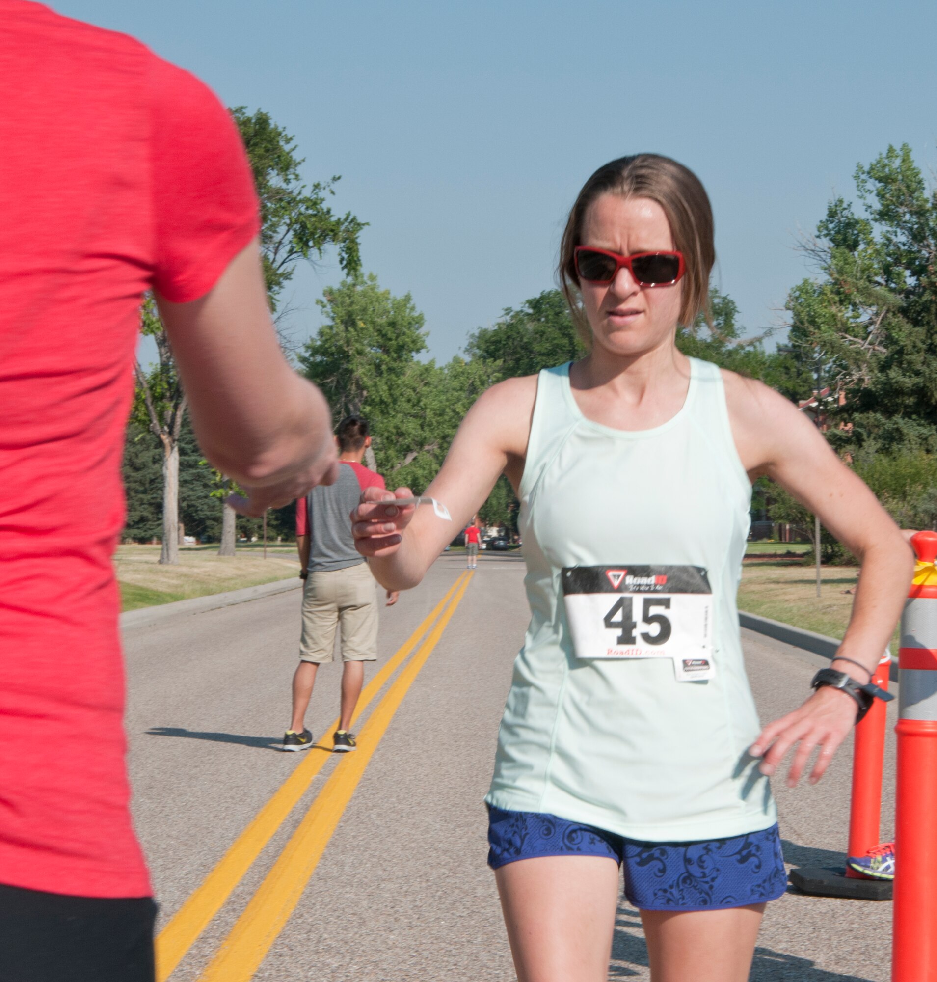 Kristi Racines, Cheyenne resident, finishes the Buffalo Stampede 5K race and hands a timing tag with identifying information to a race coordinator for accurate timekeeping July 19, 2014, near the Argonne Parade Field. This is the fourth year Racines competed in the Buffalo Stampede. (U.S. Air Force photo by Airmen 1st Class Jason Wiese)