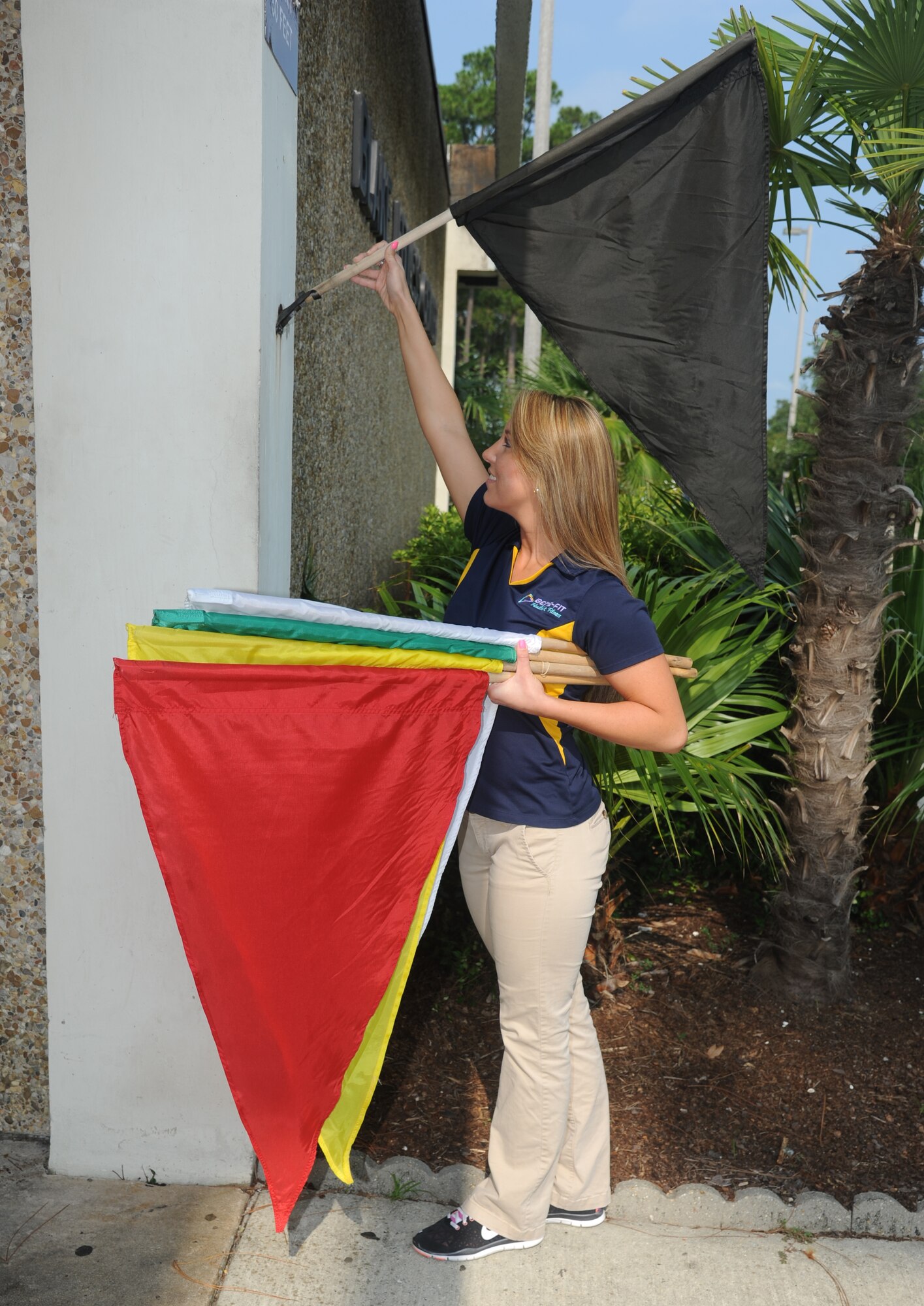 Monica Funk, from the Blake Fitness Center, posts a black flag outside the building July 21, 2014, at Keesler Air Force Base, Miss. Flags are posted outside each of the base fitness centers and the south side of the Levitow Training Support Facility to indicate heat levels throughout the day. (U.S. Air Force photo by Kemberly Groue)