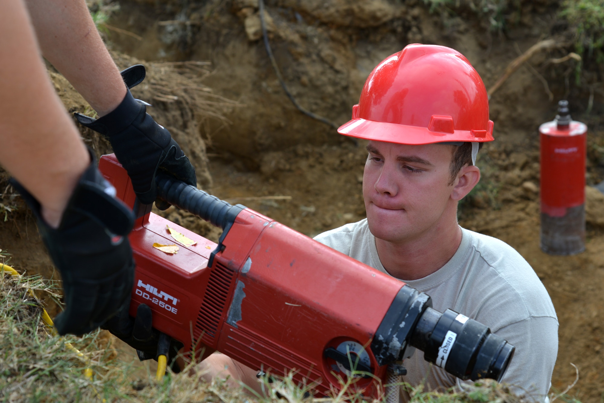 U.S. Air Force Staff Sgt. Andrew Goodrick, 820th Rapid Engineer Deployable Heavy Operational Repair Squadron Engineer electrician from Nellis Air Force Base, Nev., takes hold of a part to an electric core drill while performing construction at Langley Air Force Base, Va., July 22, 2014. The visiting REDHORSE electricians are working to repair old electrical circuits by replacing underground infrastructure. (U.S. Air Force photo by Senior Airman Aubrey White/Released) 