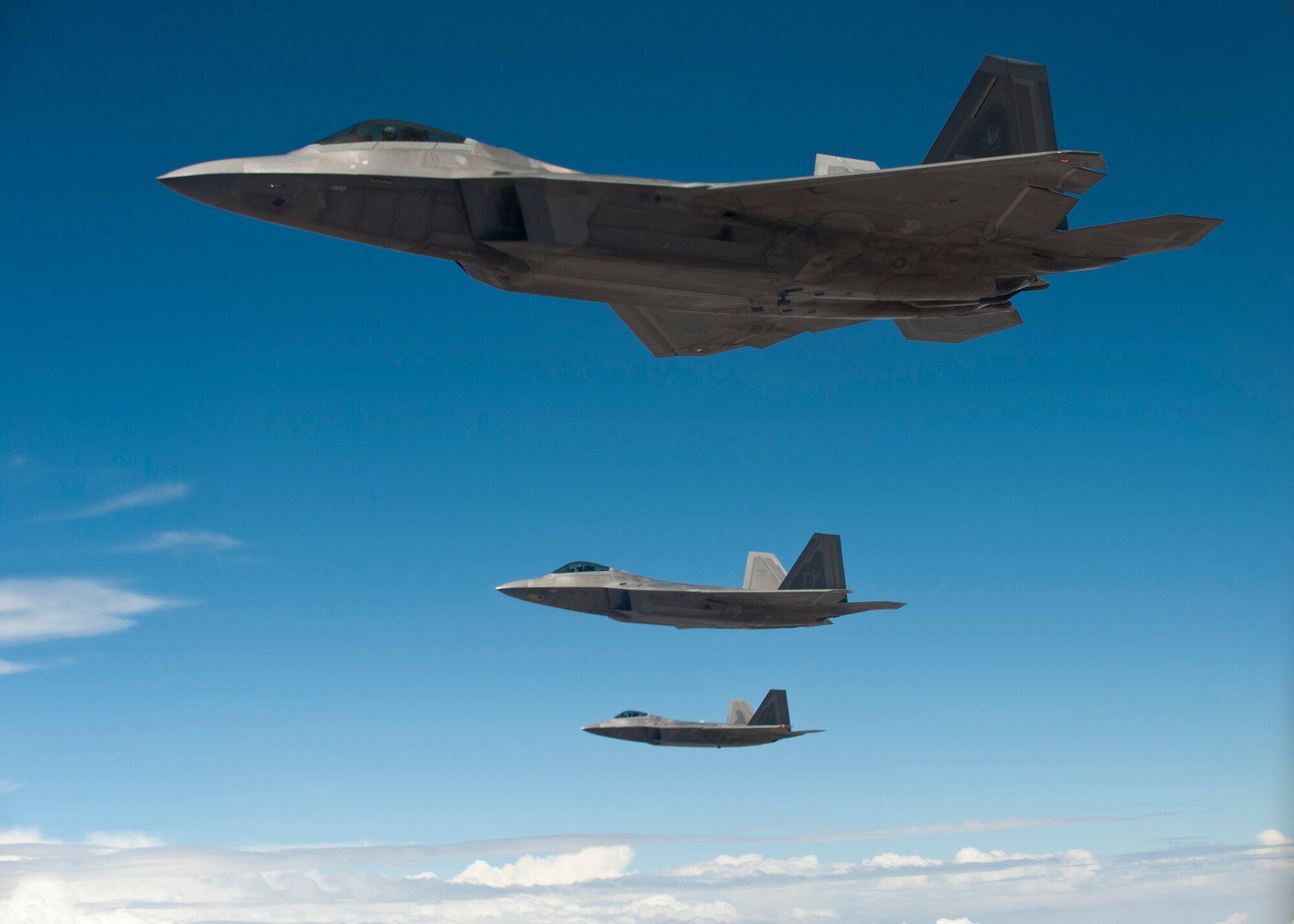 Three U.S. Air Force F-22 Raptors assigned to the 325th Fighter Wing, Tyndall Air Force Base, Fla., fly alongside a KC-135 Stratotanker assigned to the 93rd Air Refueling Squadron, Fairchild AFB, Wash., after completing in-flight refueling during Red Flag 14-3, July 17, 2014, over the Nevada Test and Training Range. Red Flag invites different units, airframes, branches and allied nations the chance to practice various air combat scenarios with one another. These different groups may have to work with one another in future real-world operations. (U.S. Air Force photo by Airman 1st Class Thomas Spangler)