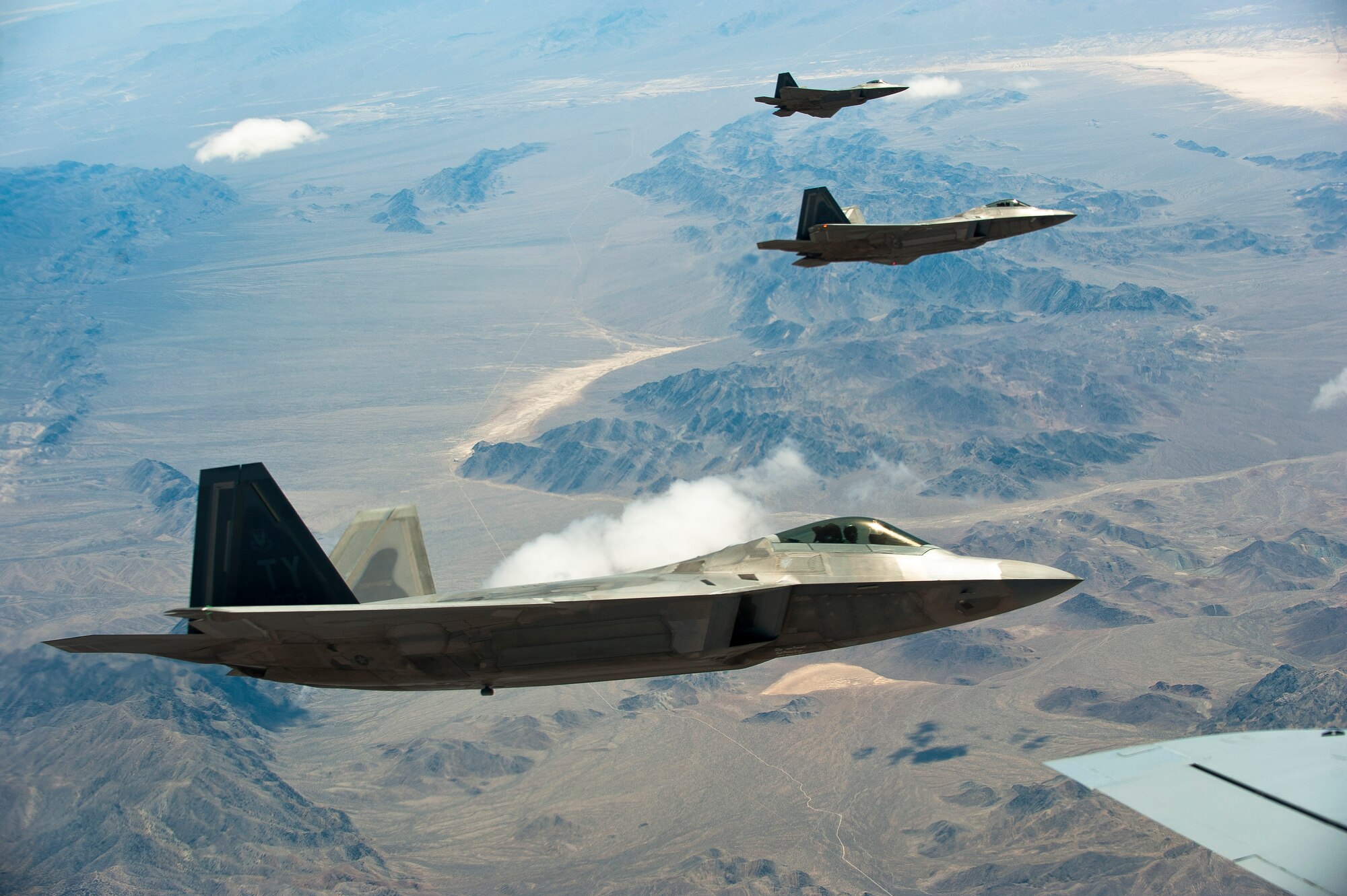 Three U.S. Air Force F-22 Raptors assigned to the 325th Fighter Wing, Tyndall Air Force Base, Fla., fly alongside a KC-135 Stratotanker assigned to the 93rd Air Refueling Squadron, Fairchild AFB, Wash., during Red Flag 14-3, July 17, 2014, over the Nevada Test and Training Range. Red Flag provides a series of intense air-to-air combat training exercises designed to increase combat readiness and effectiveness. (U.S. Air Force photo by Airman 1st Class Thomas Spangler)