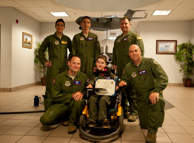Max High, son of Capt. Aaron High, 15 AS pilot, poses with his dad, Capt. Aaron High, Lt. Col. Cassius Bentley, 15th Airlift Squadron commander, 1st Lt. William Hock, 1st Lt. James Schuh Maj. Jonathan Fruge, during a tour of the 15th Airlift Squadron as part of the Pilot for a Day program. The 15th AS recognized Max as a member of the squadron and also gave him a tour of the squadron and a C-17, allowed him to co-pilot a simulator and presented him with a pilot’s jacket, scarf and pilot wings. (Air Force photo by Staff Sgt. William A. O’Brien)