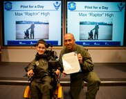 Lt. Col. Cassius Bentley, 15th Airlift Squadron commander, presents Max High, son of Capt. Aaron High, 15th AS pilot, with a certificate recognizing him as an honorary member of the squadron as part of the Pilot for a Day program July 15, 2014. The goal of the Pilot for a Day program is to provide children who have serious or chronic conditions and their families with the opportunity to be a guest of one of Joint Base Charleston’s squadrons for a day. Max also received a pilot’s jacket, scarf and pilot wings, co-piloted a C-17 simulator and toured a C-17. (Air Force photo by Staff Sgt. William A. O’Brien)