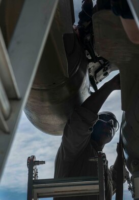Staff Sgt. Kelvin McCrea, 5th Aircraft Maintenance Squadron weapons load team chief, rests against a ladder as he works on a bomb rack during a load crew competition on Minot Air Force Base, N.D., July 11, 2014. McCrea’s four-man team competed against another crew for the title of load crew of the quarter. (U.S. Air Force photos/Airman 1st Class Lauren Pitts)  