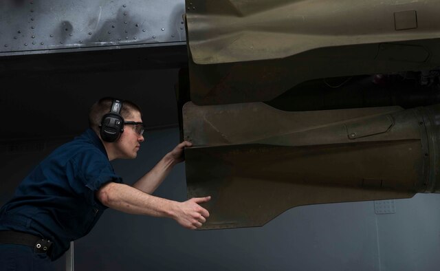 Senior Airman Jason Byrge, 5th Aircraft Maintenance Squadron weapons load crew member, directs his wingman as they attempt to fasten a bomb to a bomb-rack during a load crew competition on Minot Air Force Base, N.D., July 11, 2014. The crews compete to see who can complete their mission in the least amount of time, while being safe and efficient. (U.S. Air Force photos/Airman 1st Class Lauren Pitts) 
