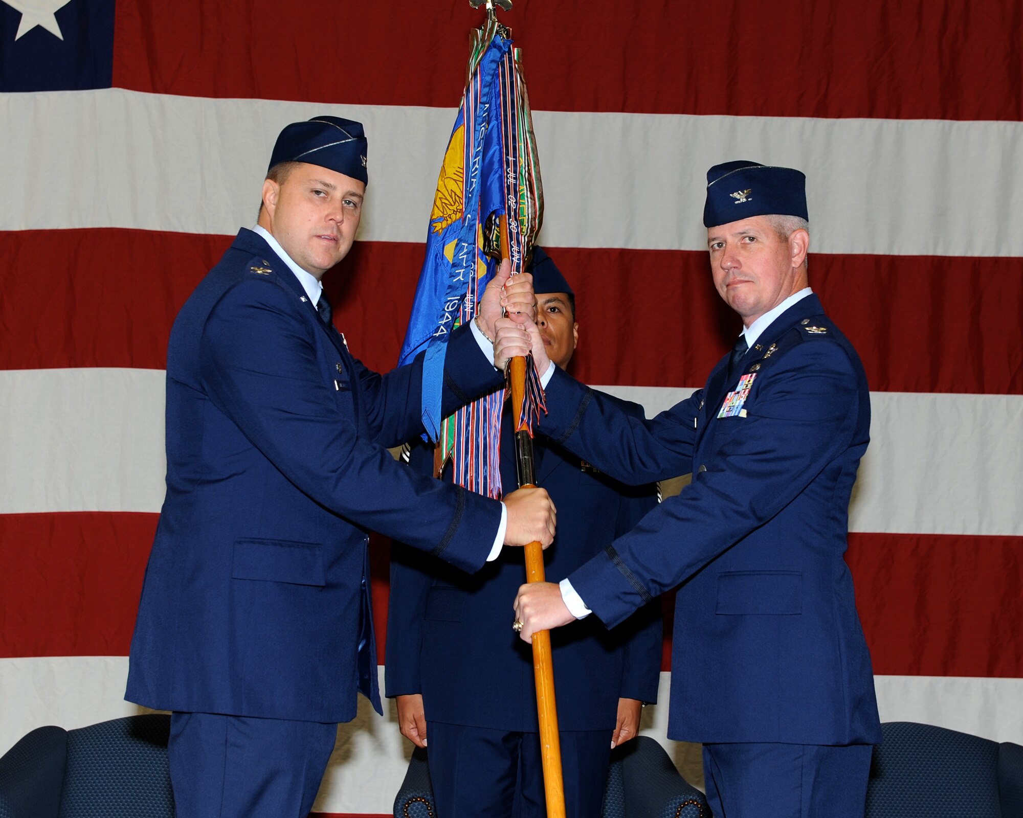 Col. John Nichols, 14th Flying Training Wing Commander, hands the guidon for the 14th Operations Group to Col. James Boster during the 14 OG Change of Command Ceremony, July 18, 2014 at the Columbus Air Force Base Crash and Fire Department. Before arriving at Columbus Air Force Base, Boster was the Chief of Staff of U.S. Air Forces Central Command, Shaw Air Force Base, South Carolina. (U.S. Air Force photo/ Elizabeth Owens) 


