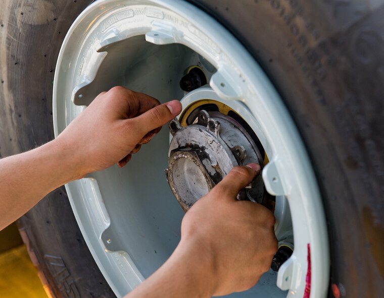 Senior Airman Dexter Pabingwit, 736th Aircraft Maintenance Squadron crew chief, installs the axle nut and anti-rotation plate assembly onto a C-17A Globemaster III nose landing gear axle July 16, 2014, at Dover Air Force Base, Del. The axle nut and anti-rotation plate assembly prevents the wheel and tire assembly from coming off. (U.S. Air Force photo/Roland Balik)