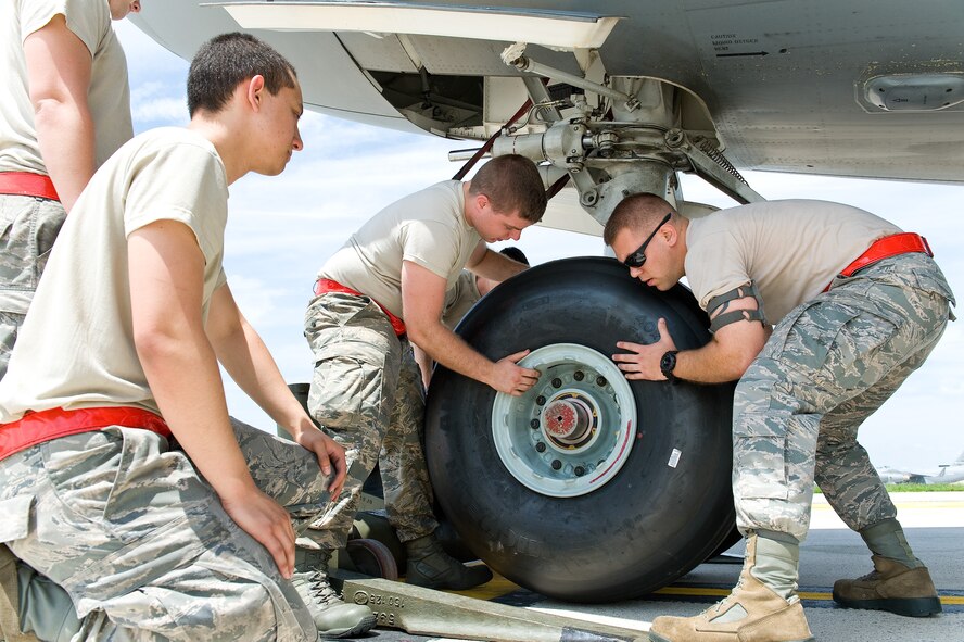 Senior Airman Dexter Pabingwit, left, watches Airman 1st Class Keenan White, center, and Josh York, right, all 736th Aircraft Maintenance Squadron crew chiefs, slide a new C-17A Globemaster III nose landing gear wheel and tire assembly onto the axle July 16, 2014, at Dover Air Force Base, Delaware. They also removed and replaced the nose landing gear wheel and tire assembly on the other side with a new assembly to prevent shimmying. (U.S. Air Force photo/Roland Balik) 

