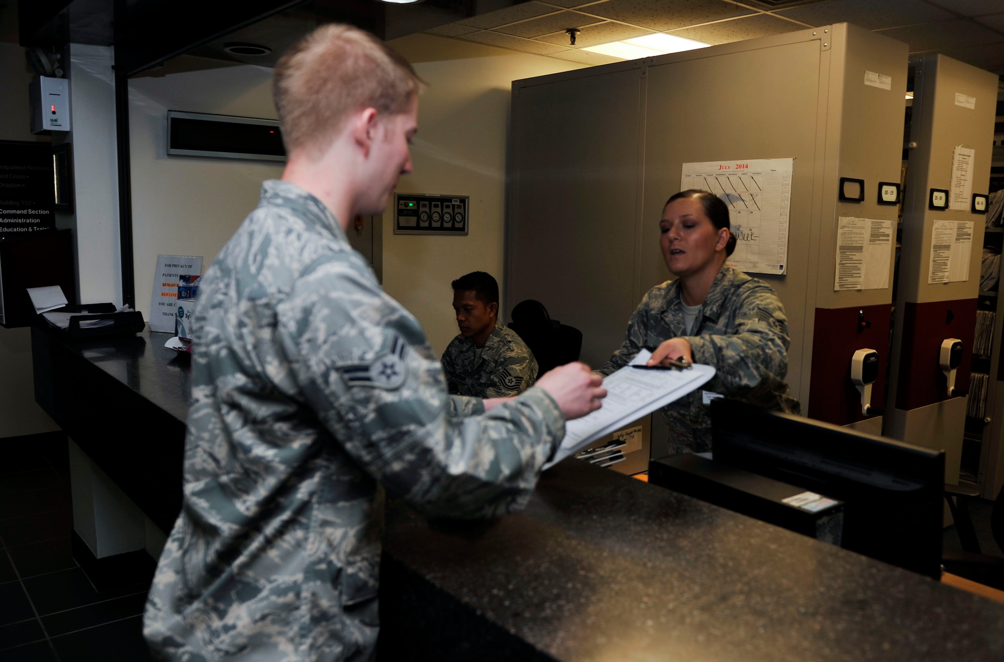 Staff Sgt. Jennifer Romine, 51st Dental Squadron readiness NCO in charge, hands examination paperwork to Airman 1st Class Tanner Peterson, 51st Logistics Readiness Squadron refueling mechanic, prior to his annual exam on Osan Air Base, Republic of Korea, July 16, 2014. The 51st DS sees approximately 100 to 130 patients daily. (U.S. Air Force photo by Senior Airman David Owsianka)