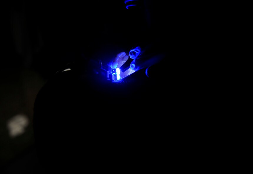 Senior Airman Anna Pauline Magno, 51st Dental Squadron dental assistant, holds a composite curing light to the teeth of Staff Sgt. Devin Elliot, 51st Force Support Squadron, during a filling restoration procedure on Osan Air Base, Republic of Korea, July 16, 2014. The composite curing light helps fillings bond with teeth. (U.S. Air Force photo by Senior Airman David Owsianka)