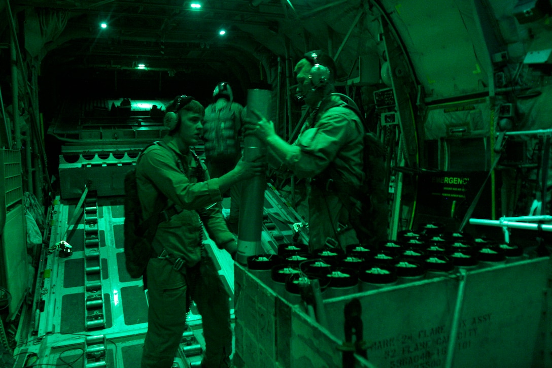 U.S. Marine Corps Cpl. Jacob Hall, left, takes a flare from U.S. Marine Corps Sgt. Christopher Weins to place into a flare chute during a battlefield illumination mission near Camp Bastion, Afghanistan, July 18, 2014. Hall, a crew chief, and Weins, a loadmaster, are assigned to Marine Aerial Refueling Transportation Squadron 352.