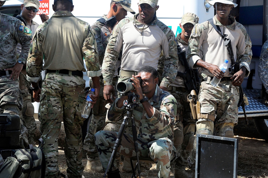 Belizean and Jamaican special operations forces team members watch their counterparts shoot on a range during a weapons familiarization event at the Colombian National Training Center on Fort Tolemaida, Colombia, July 21, 2014.