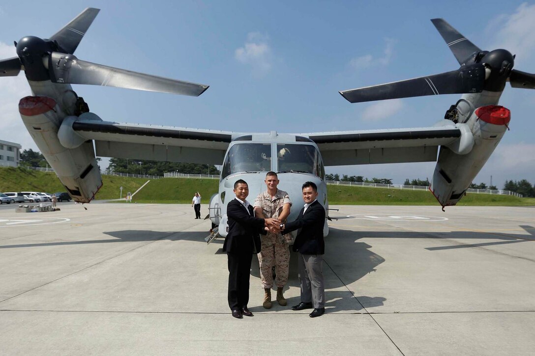 From left to right, Yohei Wakabayashi, Gotenba mayor; U.S. Marine Corps Col. James R. Fullwood Jr., camp commander of the Combined Arms Training Center Camp Fuji; and Takeru Yoshikawa, member of the diet political party, pose for a group photo in front of the MV22 Osprey on the Combined Arms Training Center Camp Fuji, Japan, July 15, 2014. The Marines with Marine Medium Tiltrotor Squadron 265, Marine Aircraft Group 36, 1st Marine Aircraft Wing, III Marine Expeditionary Force mission while in the Combined Arms Training Center Camp Fuji was to determine the possibility of future landing zones for the MV22 Osprey. 
(U.S. Marine Corps photo by MCIPAC Combat Camera Lance Cpl. Luis A. Rodriguez III/ Released)
