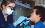 Army Capt. Martha Mitchell, a dentist at the U.S. Army Garison-Stuttgart Dental Clinic, examines 7-year-old Parker Weedon's teeth during a visit to his second-grade classroom at Robinson Barracks Elementary School. Assistance for family dental care up to $4,000 per case is now available through Army Emergency Relief under new guidelines that expand eligible categories.