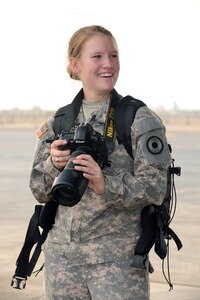 Army Spc. Michelle Lawrence, 35th Military Police Company combat medic currently serving as a unit public affairs representative for the 1st Battalion 161st Field Artillery, Kansas Army National Guard, adjusts her camera settings at Camp Lemonnier, June 30, 2011. Lawrence is a combat medic, but was designated as a unit public affairs representative for the 1-161 FA BN shortly after deploying to Africa. She calls Dighton, Kan., home.