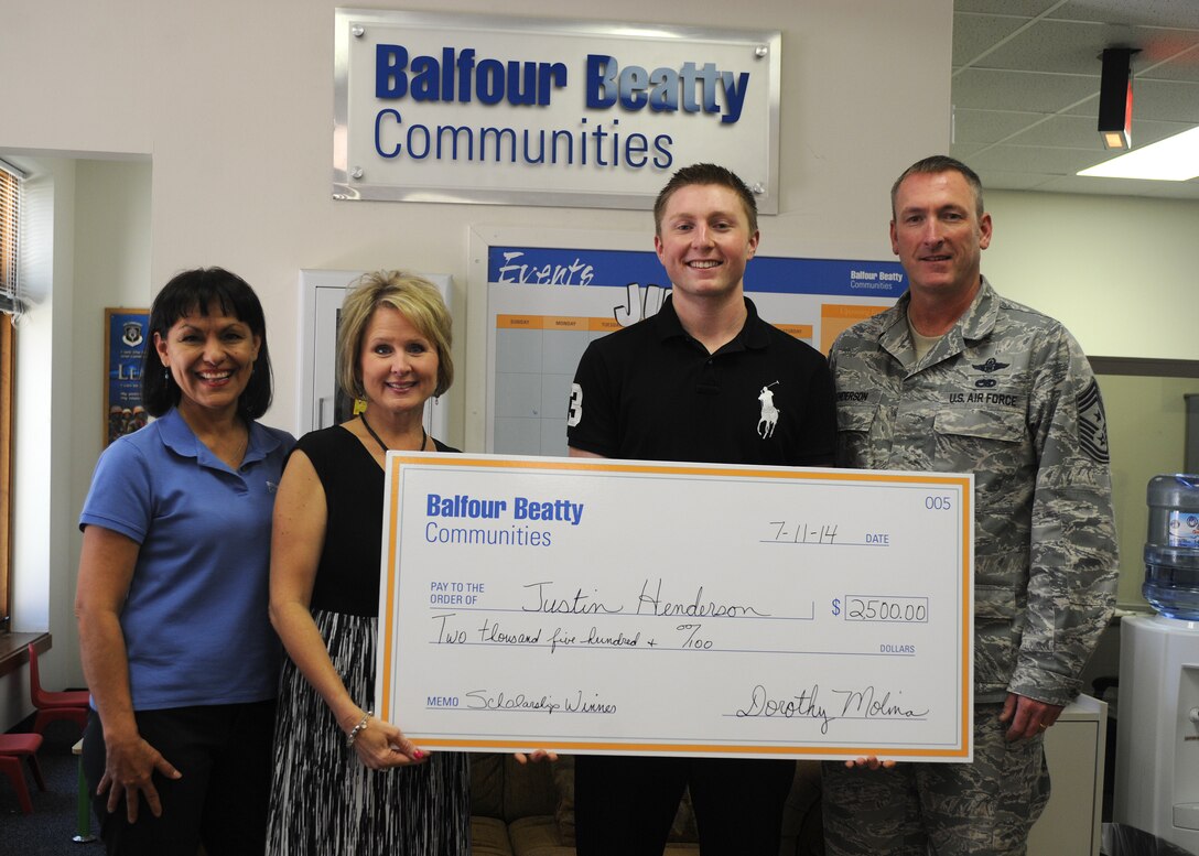 U.S. Air Force Chief Master Sgt. Paul Henderson, 27th Special Operations Wing command chief, stands with his son, Justin and wife, Tammy, and Dorothy Molina, Balfour Beatty Communities community manager, as his son is awarded a scholarship for $2,500. The BBC foundation holds an annual scholarship contest every year for members of the military community. (U.S. Air Force photo/Senior Airman Ericka Engblom)