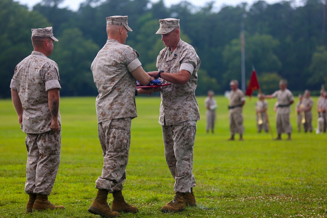 Sgt. Maj. Scott L. Theakston accepts a flag from the retiring official during the School of Infantry - East relief and appointment ceremony and retirement ceremony at Camp Geiger aboard Marine Corps Base Camp Lejeune, June 27. Theakston retired from the Marine Corps after 30 years of service, handing over his position to Sgt. Maj. Robert H. Brown Jr. (Official U.S. Marine Corps photo by Lance Cpl. Jared Lingafelt)


