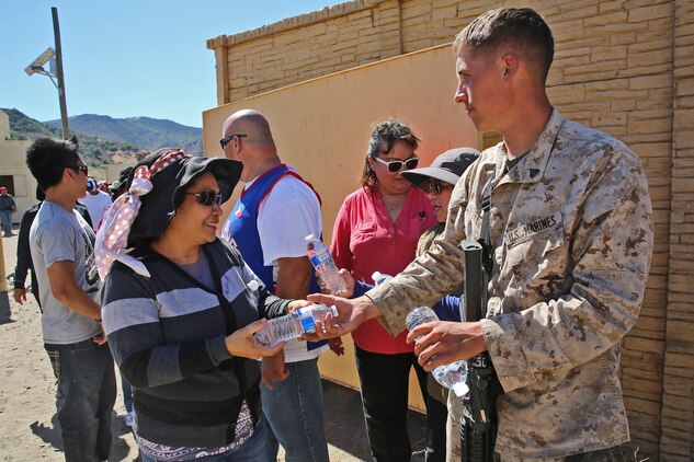 Corporal Michael Beck, an electrician with Combat Logistics Battalion 15, 1st Marine Logistics Group, provides water to a crowd of role-players during a humanitarian aid exercise as part of CLB-15’s pre-deployment training taught by the Special Operations Training Group, 1st Marine Expeditionary Force, aboard Camp Pendleton, Calif., July 16, 2014. The exercise took place over the course of three days, and provided CLB-15 with a realistic and immersive experience. The simulation, set up by SOTG with the help of the USAID, put CLB-15’s Marines and sailors in the middle of a typhoon-ravaged rural Philippine area where they were tasked with providing humanitarian aid and disaster relief, similar to the situation faced by Marines with the 3rd Marine Expeditionary Force during the aftermath of Typhoon Haiyan in 2013. CLB-15 is slated to deploy with the 15th Marine Expeditionary Unit, 1st Marine 
Expeditionary Force.