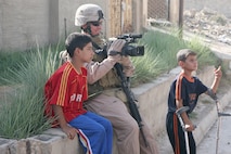 Staff Sergeant Christian Foucart, Second Marine Expeditionary Force (II MEF), Combat Camera video tapes a patrol in Al Fallujah, Iraq on September 5, 2007. Marines are assisting Iraqi Police in the distribution of food and soccer balls by proving transportation and security.   II MEF is deployed in support of Operation Iraqi Freedom in the Al Anbar province of Iraq to develop Iraqi Security Forces, facilitate the development of official rule of law through democratic reforms, and continue the development of a market based economy centered on Iraqi reconstruction. (Official USMC photo by MSgt Paul D. Bishop) (Released)