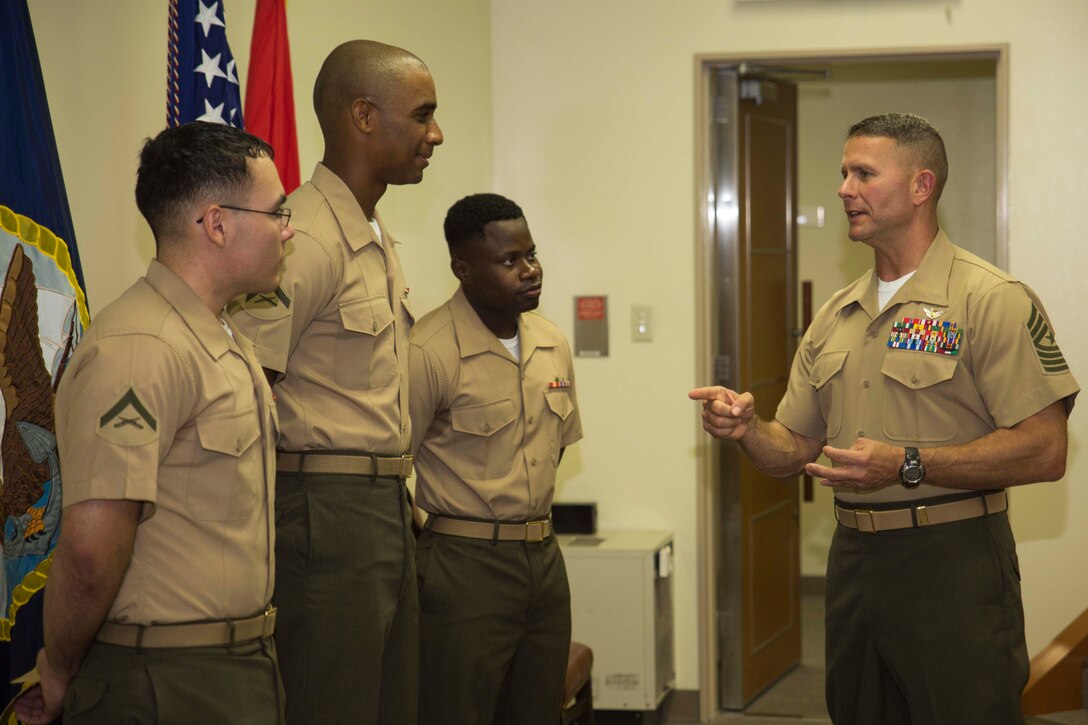 Sgt. Maj. Keith Massi, Station sergeant major, talks to (from left to right) Lance Cpls. Jorge Meza and Shaqueal Coote and Pfc. Kervens Beauplan after their naturalization ceremony aboard Marine Corps Air Station Iwakuni, Japan, July 17, 2014. The naturalization ceremony was held to award the Marines their U.S. citizenship.
