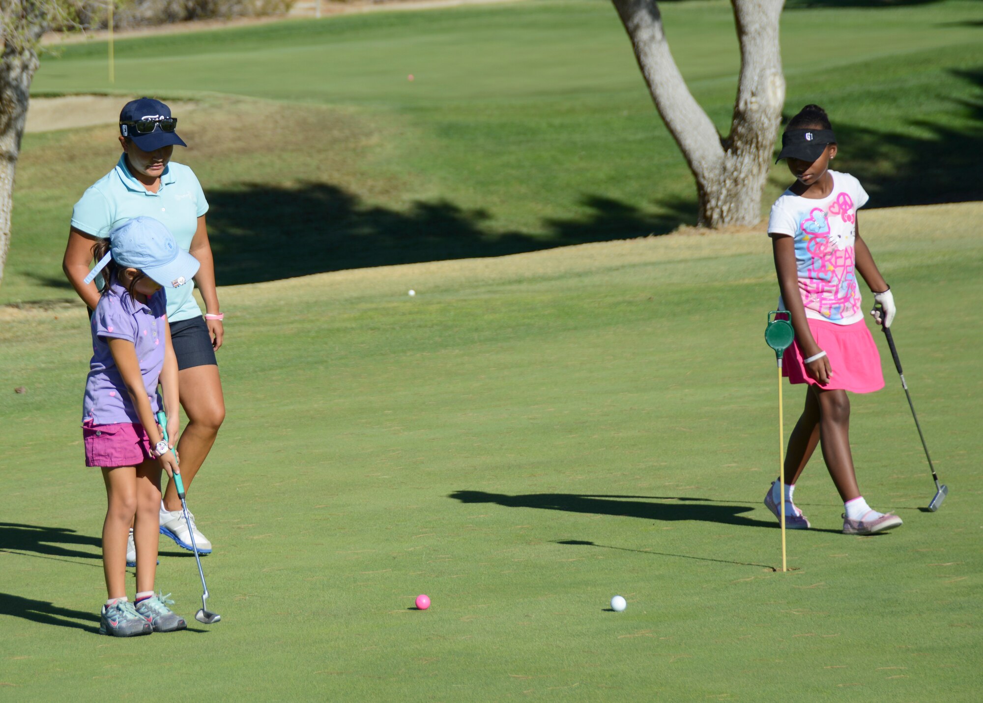 Golf instructor Chelsea Orozco (center) teaches Anna (left) and Zahria (right) how to improve their putting technique during a junior golf clinic at Muroc Lake Golf Course July 23. (U.S. Air Force photo by Rebecca Amber)