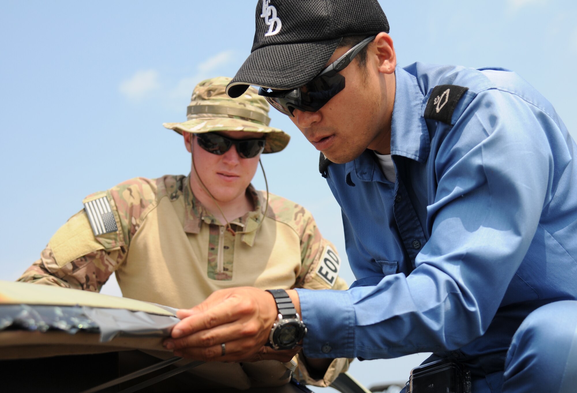 U.S. Air Force Airman 1st Class Anthony Donelan, 35th Civil Engineer Squadron explosive ordnance disposal apprentice, monitors Japanese Maritime Self-Defense Forces Petty Officer 2nd Class Yoshimasa Ogawa, EOD member, tape explosive wiring at the Draughon Bombing Range, Misawa Air Base, Japan, July 15, 2014. After demonstrating techniques on how to properly wire certain vehicle access explosives, U.S. service members allowed their EOD counterparts from the JMSDF to accomplish the task themselves with close monitoring. (U.S. Air Force photo/Senior Airman Jose L. Hernandez-Domitilo)
