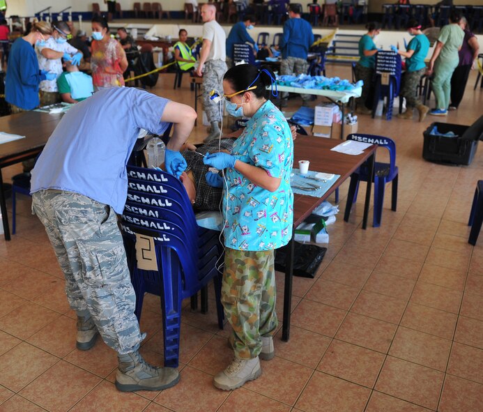 U.S. Air Force Capt. Jeremy Matis, a dentist, and Royal Australian Air Force Corporal Terri-Anne Dehncke, senior dental assistant-preventative, perform an extraction, Neiafu, Vava???u, July 22, 2014. The dental clinic was set up in a local college for the Pacific Angel-Tonga healthcare services outreach. Matis is deployed from Eielson Air Force Base, Alaska and Dehncke is from RAAF Base Richmond, New South Wales. (U.S. Air Force photo by Staff Sgt. Rachelle Coleman/Released)
