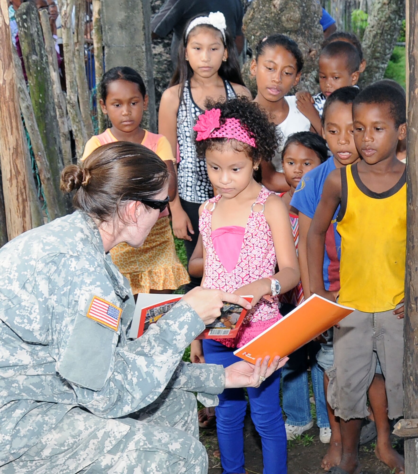 U. S. Army Capt. Erin Velazquez gives a Honduran child a Spanish reading book during a MEDRETE.  Joint Task Force -Bravo's Medical Element (MEDEL), with support from 1-228th Aviation Regiment, JTF-Bravo Joint Security Forces and Army Forces Battalion, partnered with the Honduras Ministry of Health and the Honduran military to provide medical care to more than 650 people in the remote village of Barra Patuca in the Department of Gracias a Dios, Honduras, during a Medical Readiness Training Exercise (MEDRETE), July 17, 2014.  The multi-national team worked together to provide preventative medicine to the villagers, including classes on hygiene, preventative dental care, and nutrition. They also provided immunizations to infants, dental care, wellness checkups, medications, and minor medical procedures.  (Photo by U. S. Air National Guard Capt. Steven Stubbs)