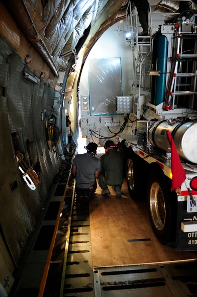 Two crew members from NASA’s Goddard Space Flight Center watch the tight clearance between the the cargo and C-5C Galaxy's fuselage during the careful unloading process at Joint Base Andrews, Md., July 17, 2014.  This C-model Galaxy from the 22nd Airlift Squadron at Travis Air Force Base, Calif., is one of two “space cargo modified” Galaxies in the Air Force fleet.  The planes were customized to carry satellites and large cargo, and routinely support the NASA mission by delivering assets throughout the nation. (U.S. Air Force photo/Staff Sgt. Torey Griffith)