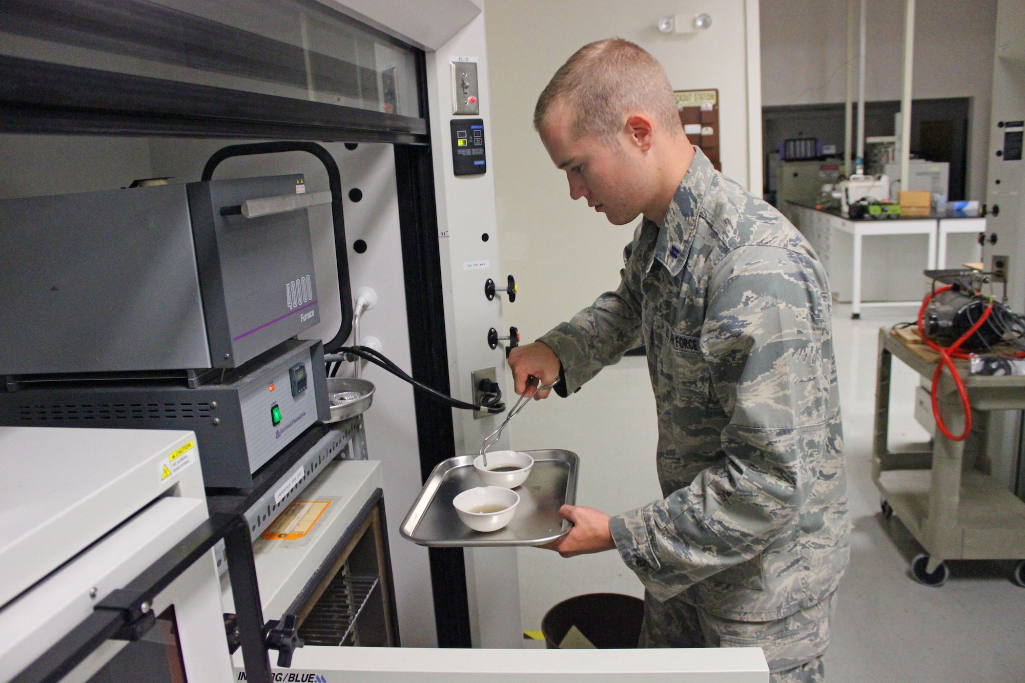 U.S. Air Force Academy Cadet Marcus Penner places samples from an anaerobic digester into a laboratory oven at the Air Force Civil Engineer Center’s Readiness Directorate at Tyndall Air Force Base, Fla., recently. The test is designed to measure the solid content of the digestate to determine how well the digester is performing. Penner worked with AFCEC scientists during a six-week research project to test and develop a system to convert food waste to methane gas as a potential energy source at expeditionary bases. (U.S. Air Force photo/John Burt/Released)