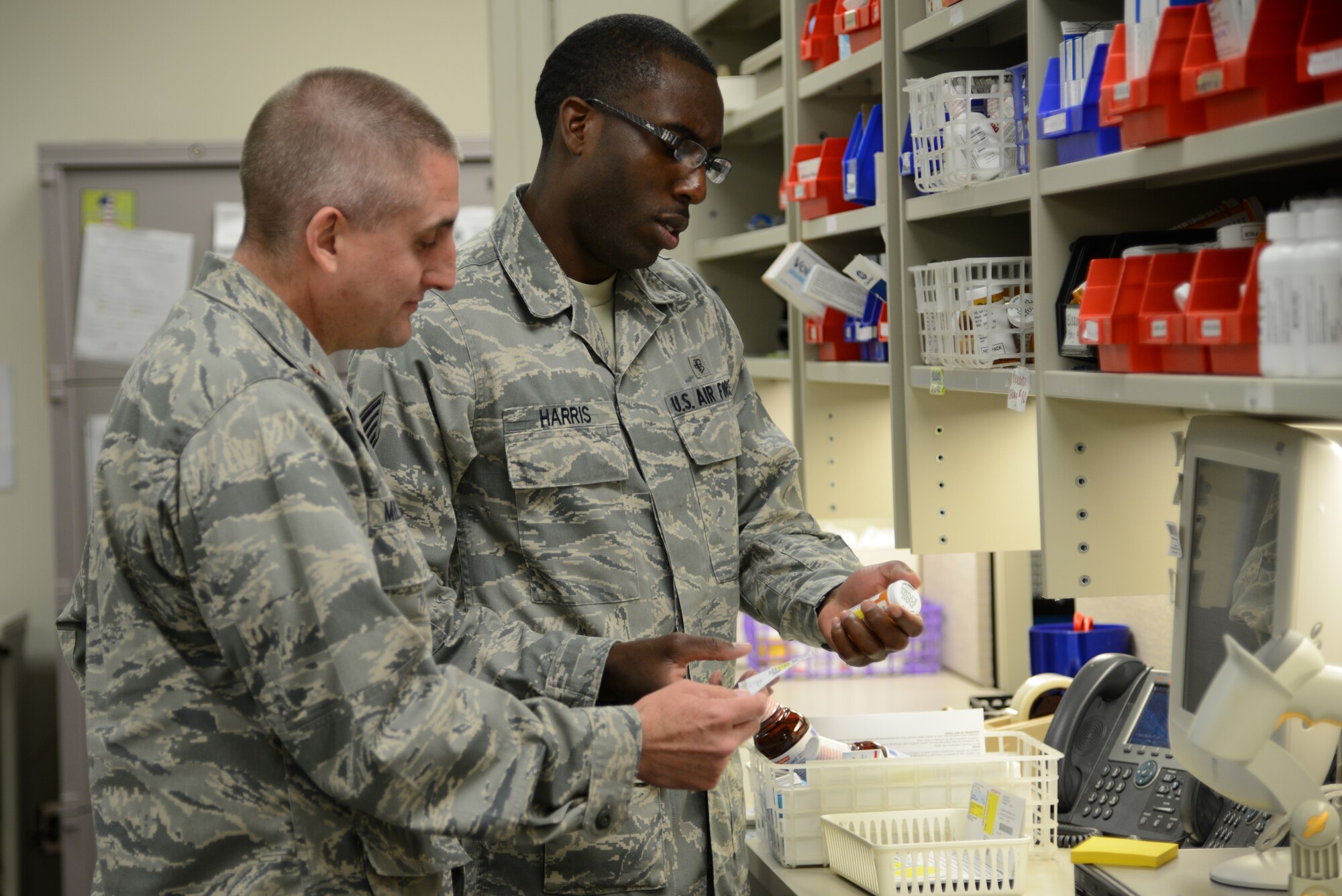U.S. Air Force Reserve Staff Sgt. Jermaine Harris, 445th Aerospace Staging Squadron pharmacy technician, inquires about a patient’s medication dosage with Maj. Charles Miller, 445th ASTS pharmacist, during their tour of USAF Hospital Langley at Langley Air Force Base, Va., July 21, 2014. Miller said his three biggest priorities behind the counter are to ensure patients get the correct medication, the dosages are accurate and the medication is handled with the utmost safety. The Reservists completed their required biannual training for their career-specific duties to ensure they are prepared to deploy if called upon. (U.S. Air Force photo by Airman 1st Class Devin Scott Michaels/Released)