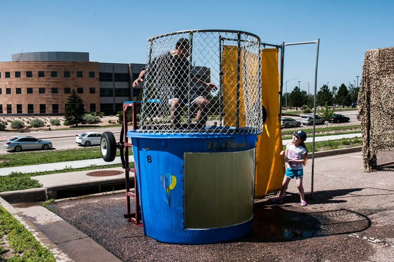 Col. Bill Liquori, 50th Space Wing commander, waits as Sarah Ford attempts to dunk him during the Summer Slam Base Picnic July 18, 2014, at Schriever Air Force Base, Colo. The base picnic was part of Schriever Week, a weeklong celebration that honored the installation's history and recognized the people who support the daily mission. (U.S. Air Force photo/Staff Sgt. Julius Delos Reyes)
