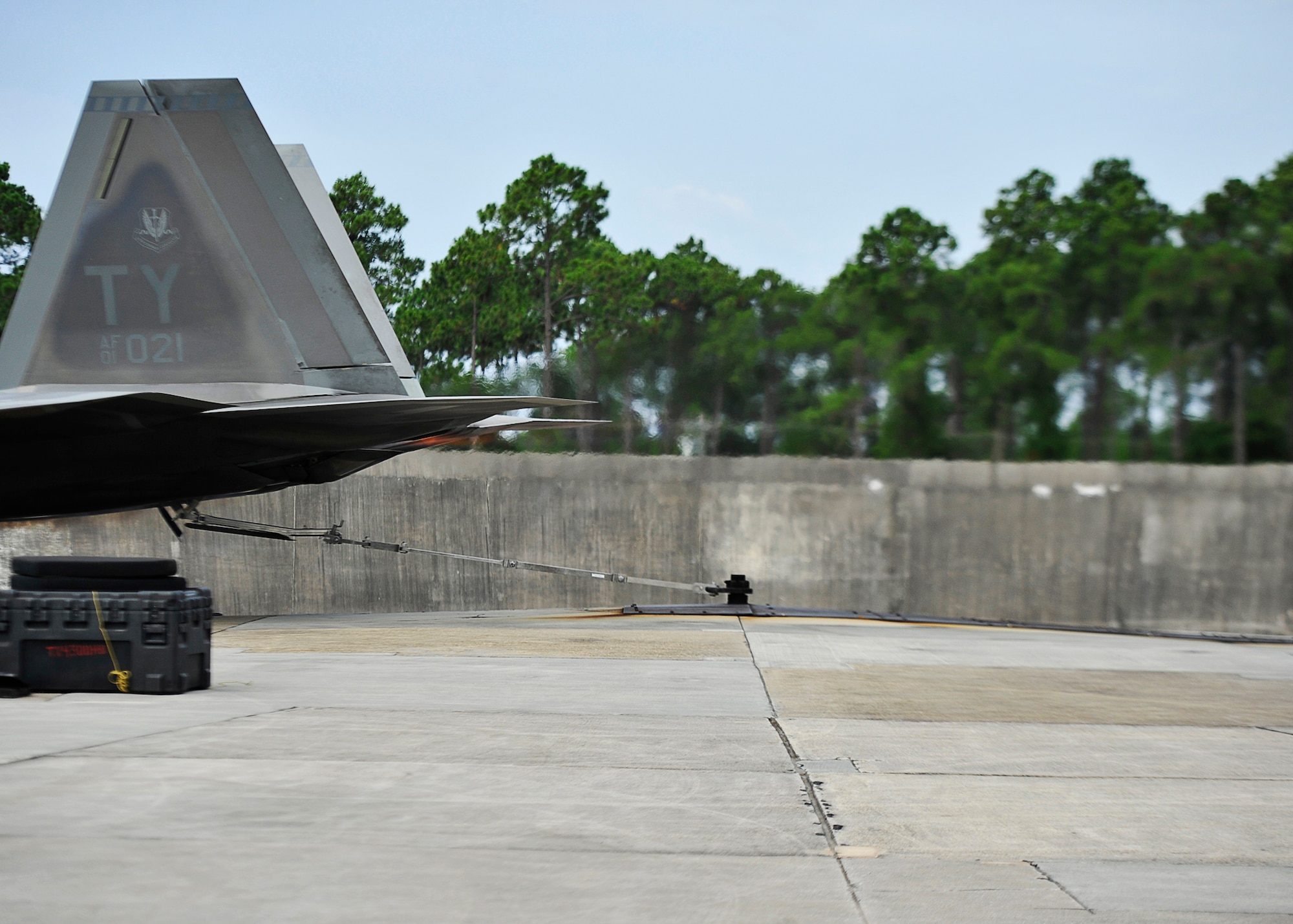 An F-22 Raptor is securely tethered to the center of an engine testing zone during the final phase for student maintainer certification 18 July during an operational engine run at Tyndall. Phase three is the culmination of academic, simulator and hands-on training after a prerequisite of six months airframe training and supervisor recommendation. (U.S. Air Force photo by Tech. Sgt. Javier Cruz/Released)