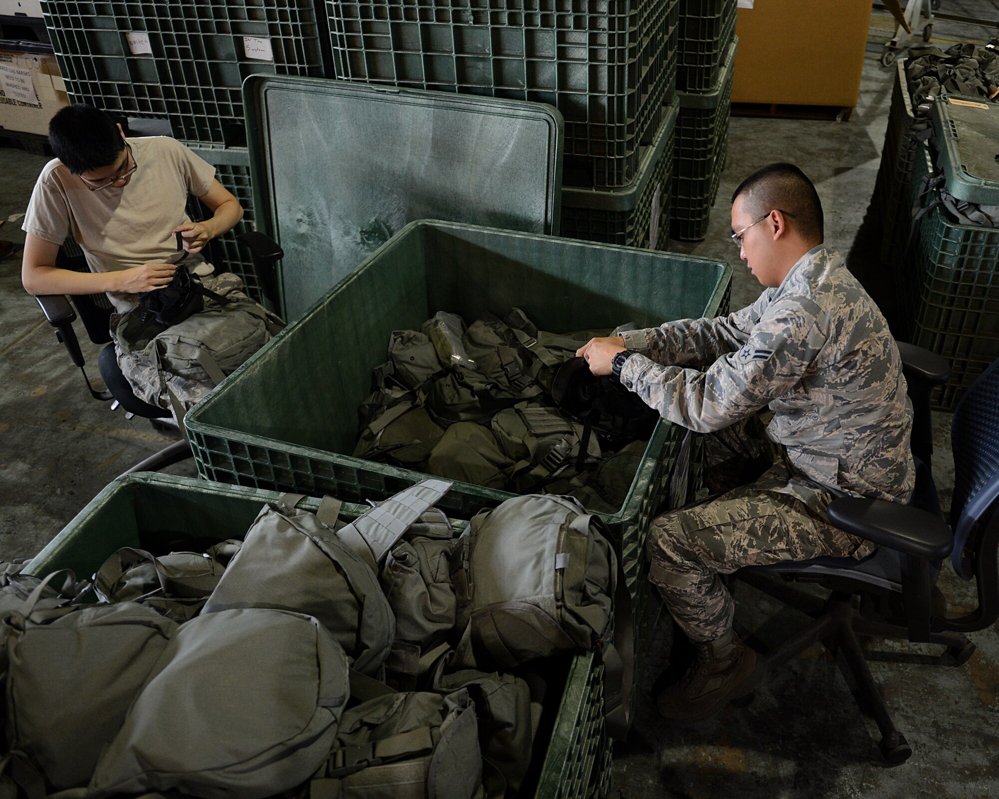 Airmen 1st Class Steve Pak, left, and Karl Santos, 2nd Logistics Readiness Squadron mobility section, place headstraps on M-50 Gas Masks on Barksdale Air Force Base, La., July 21, 2014. They inspect all gas masks that have been returned within the last six months for serviceability. (U.S. Air Force photo/Senior Airman Benjamin Gonsier)