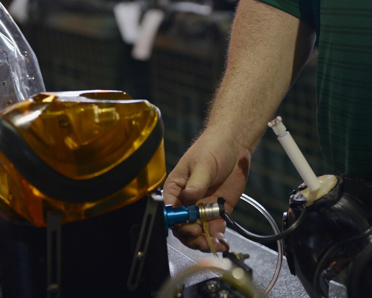 Roger Jordan, a contractor from Tyndall Air Force Base, Fla., tests the drinking tube of an M-50 Joint Service General Purpose Mask for blockage on Barksdale Air Force Base, La., July 21, 2014. In order to test the drinking tube for leakage, the tube is inserted into a Joint Service Mask adapter kit, which transfers air into the tube and tests the air pressure inside. Little or no air pressure means there is leakage in the drinking tube and that it needs replacing. (U.S. Air Force photo/Senior Airman Benjamin Gonsier)